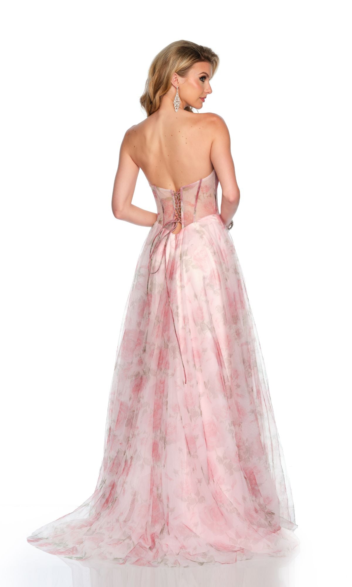 A woman faces away, wearing the Dave & Johnny Long Prom Dress 11670—a strapless, floor-length pastel pink A-line gown with floral patterns and a lace-up back.